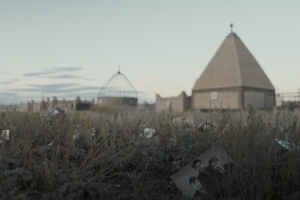 Photographs are scattered throughout the grass. There is a building with a cross in the background.