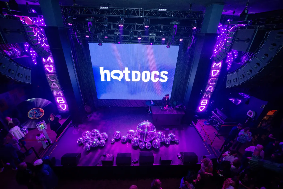 A purple-tinted photograph of a stage with "Hot Docs" projected on screen.